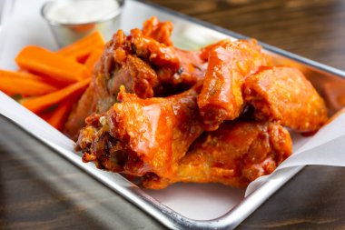 A closeup view of an appetizer tray of buffalo wings, in a restaurant or kitchen setting.