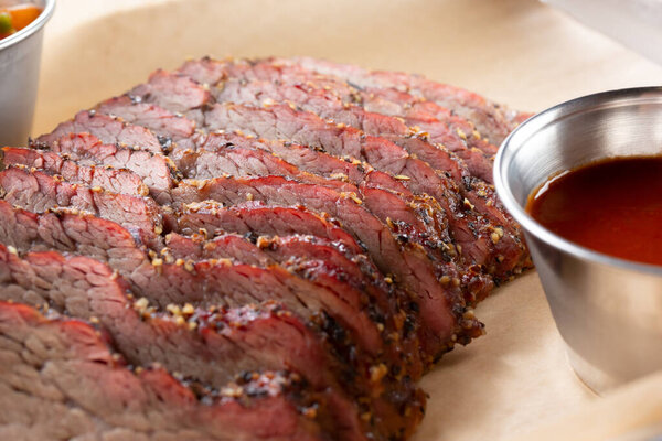 A closeup view of the texture of several tri tip meat slices on a metal tray, in a restaurant or kitchen setting.