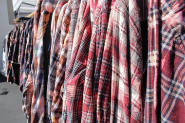 Yerel bir ikinci el mağazasında sergilenen birkaç ekose desenli uzun kollu gömleğin görüntüsü.