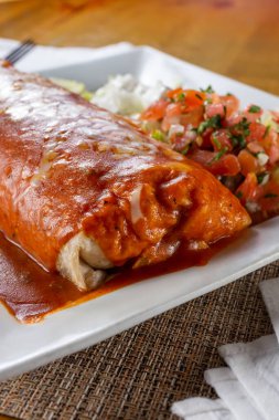 Islak bir burrito tabağının yakın çekim görüntüsü, bir restoranda veya mutfak ortamında..