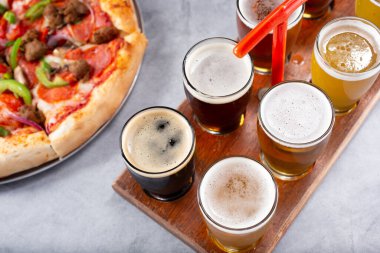 Bir pizza turtasının yanında bira uçuşu manzarası..