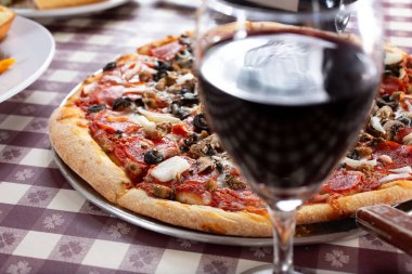 Bir İtalyan restoranında, pizzanın önünde bir bardak şarap manzarası..