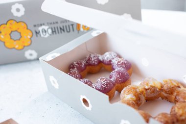 Los Angeles, California, ABD - 10-02-2021: Mochinut tarzı donutlar ve arka plandaki logo manzarası.