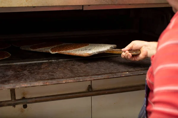 従業員が木製のパドルを使用して いくつかのManakishを置くオーブンへの眺め — ストック写真