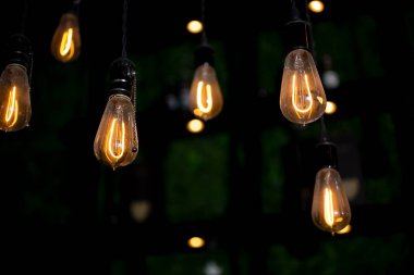 Çağdaş bir kentsel ahşap kirişinden sarkan loş antika ampul armatürlerinin görüntüsü.