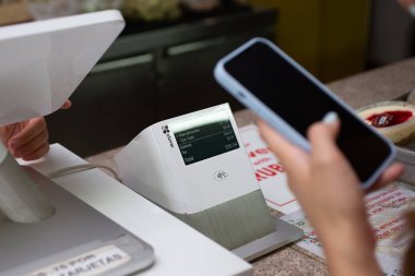 Los Angeles, Kaliforniya, ABD - 08-10-2021: Bir perakende mağazasının kasasında cep telefonu tutan bir kişinin görüntüsü, Clover satış noktasının yer aldığı bir büfe.