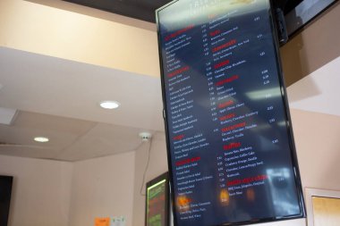 Los Angeles, Kaliforniya, ABD - 10-02-2021: Yerel bir restoranın duvarına monte edilmiş bir LCD televizyon ekranı müşterilere menüyü uygun bir şekilde görme olanağı sağlıyor.