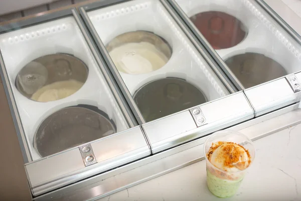 A view looking into a cold storage display inside the counter area. at a local ice cream shop, featuring a variety of flavors inside metal containers.