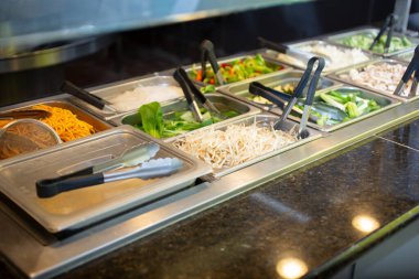 Yerel bir Moğol mangal büfesi restoranında çeşitli ham malzemelerle dolu bir buharlı tencere manzarası..