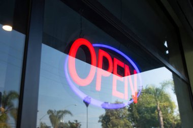 Neon ışıklı açık tabelanın olduğu bir restoran penceresi manzarası..