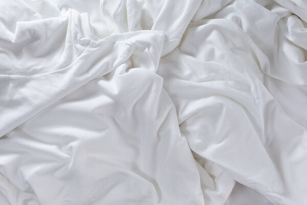 A top down view of a white natural wrinkle and folds cloth, as a background.