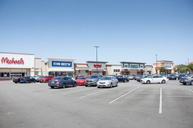Los Angeles, California, ABD - 04-26-2021: Arka planda popüler mağazaların yer aldığı bir alışveriş merkezi otoparkı manzarası.