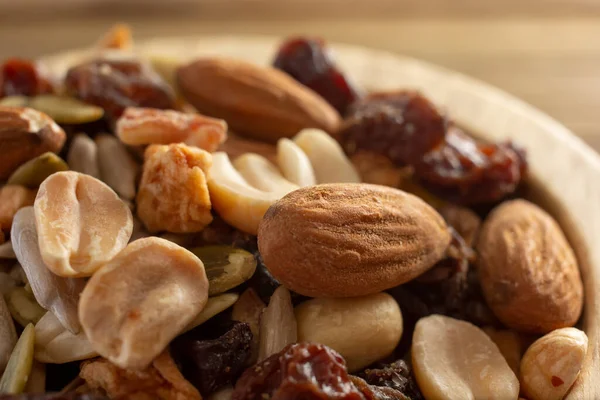 An extreme closeup view of a wood bowl of trail mix.