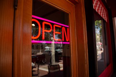 Ön kapıda bir restoran manzarası ve penceresinde neon ışığı olan bir tabela..