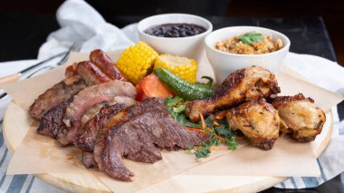 Bir et tabağı manzarası, bir restoranda ya da mutfak ortamında biftek, sosis ve tavuk..