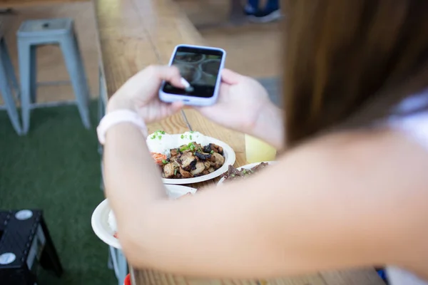 外のパティオの設定で 彼女の携帯電話で食べ物の写真を撮る女性のビュー — ストック写真