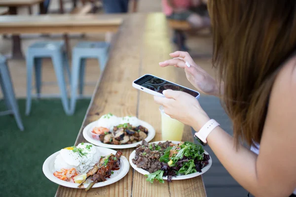 米国カリフォルニア州ロサンゼルス 2021 Iphoneを使って地元のアジア料理店の外で食べ物の写真を撮る女性の見解 — ストック写真