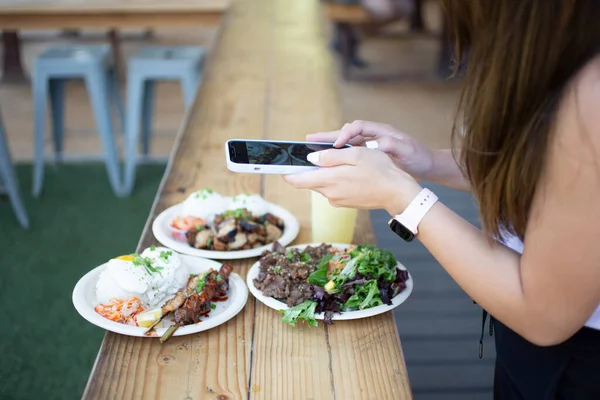 米国カリフォルニア州ロサンゼルス 2021 Iphoneを使って地元のアジア料理店の外で食べ物の写真を撮る女性の見解 — ストック写真