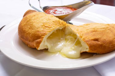 Restoranda ya da mutfak ortamında bir tabak peynirli calzone 'nin yakın çekim görüntüsü..