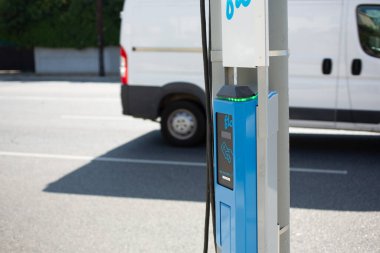 Los Angeles, California, ABD - 07-15-2021: Sokaktan geçen bir minibüsün yer aldığı FLO kaldırım kenarı elektrikli araç şarj istasyonu manzarası.