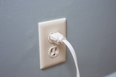 Duvar prizine bağlı beyaz bir elektrik kablosu görüntüsü.