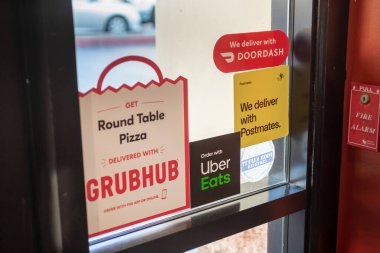 Redondo Beach, California, ABD - 01-17-2020: Yayınlanan gıda dağıtım uygulaması şirketlerinden gelen çok sayıda restoran vitrini çıkartma reklamının görüntüsü.