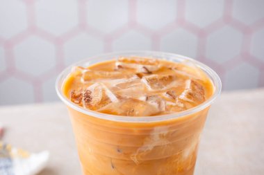 Açık plastik bardakta, bir restoranda ya da mutfak ortamında Tayland buzlu çayının yakın çekim görüntüsü.