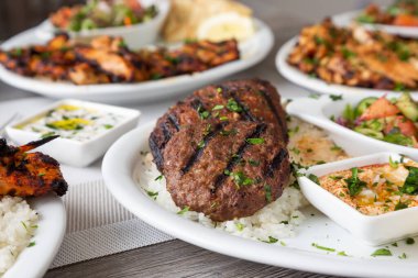 Kafta ve şiş kebap içeren bir restoran veya mutfak ortamında çok sayıda Akdeniz yemeği manzarası.