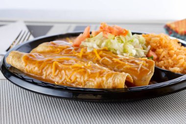 Bir tabak pirinçli iki enchilada manzarası..
