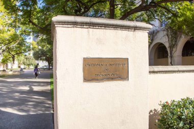 Pasadena, California, ABD - 01-31-2020: Kaliforniya Teknoloji Enstitüsü yazan bir tabela ile giriş sütununun önünden geçen bir kadının görüntüsü.