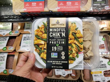 Garden Grove, California, ABD - 04-09-2020: Bir el yerel bir bakkalda sergilenmekte olan Sweet Earth Foods Mindful Chik 'n Strips paketini tutuyor.