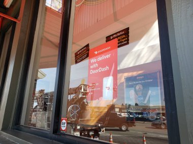 Los Angeles, Kaliforniya / ABD - 04 / 04 / 2020: Bir restoranın ön camının görünümü, kapı kontrol uygulaması aracılığıyla teslimatın ulaşılabilirliğini gösteren bir çıkartma levhası.