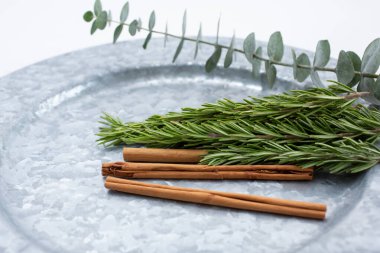 Bir tabak tarçın çubuğu, biberiye filizi ve okaliptüs dalı manzarası..
