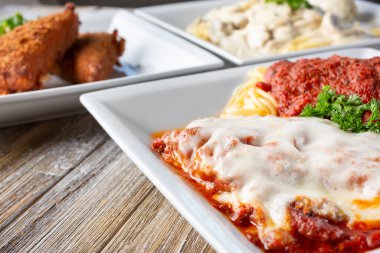 Ahşap bir masa yüzeyinde parmesanlı tavuk içeren birkaç İtalyan başlangıç tablosu..