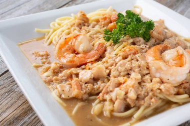 İçinde karides ve istiridye eti bulunan bir tabak sade deniz mahsulü spagettisi manzarası..