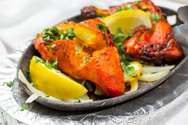 A view of a skillet plate with Tandoori chicken.