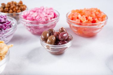 Bir cam çeşni kabı Kalamata zeytinleri, diğer çeşitli doğranmış malzemeler arasında.