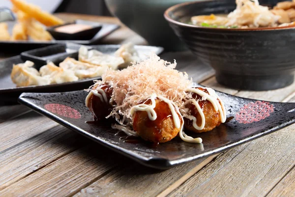 Masadaki diğer Japon aperatiflerinin yanında bir tabak takoyaki..