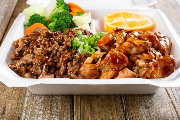 Biftek ve tavuklu teriyaki içeren konteynırın yakın çekim görüntüsü..