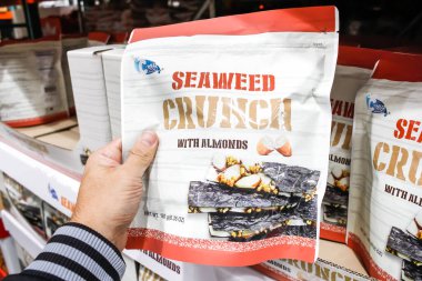 Tustin, Kaliforniya / ABD - 02 / 08 / 2020: Bir el, yerel büyük bir markette sergilenen bademli C-Weed Snack Seaweed Çıtırları paketini tutuyor.