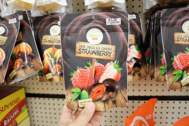 Long Beach, Kaliforniya / ABD - 02 / 12 / 2020: Bir el yerel bir bakkalda sergilenmekte olan, Doğaya özgü Kara Çikolata kaplı Çilek Atıştırmalığı paketini tutuyor.