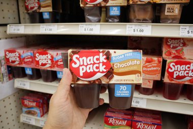 Long Beach, California, United States - 02-12-2020: A hand holds a Chocolate Snack Pack, on display at a local grocery store.