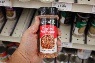 Long Beach, California, United States - 02-12-2020: A hand holds a container of Fresh Finds Crushed Red Pepper, on display at a local Big Lots.