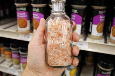 Bir el, yerel bir markette sergilenen bir şişe Himalaya pembe tuzu tutuyor..