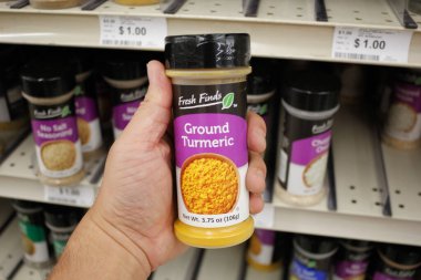 Long Beach, California/United States - 02/12/2020: A hand holds a container of Fresh Finds Ground Turmeric on display at a local Big Lots.