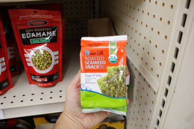 Long Beach, California/United States - 02/12/2020: A hand holds a package of Sea's Gift Roasted Seaweed Snack, on display at a local grocery store.