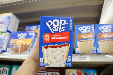 Long Beach, California/United States - 02/12/2020: A hand holds a box of Pop Tarts Frosted Strawberry, on display at a local grocery store.