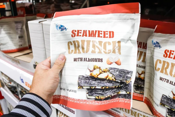 Tustin, Kaliforniya / ABD - 02 / 08 / 2020: Bir el, yerel büyük bir markette sergilenen bademli C-Weed Snack Seaweed Çıtırları paketini tutuyor.