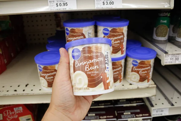 Long Beach, California, ABD - 02-12-2020: Bir el yerel bir markette sergilenen Pillsbury Yüksek Kremalı Tarçınlı Çörek konteynırını tutuyor.