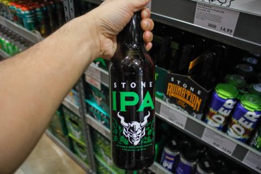 West Covina, Kaliforniya / ABD - 02 / 19 / 2020: Bir el yerel bir bakkalda sergilenmekte olan büyük bir şişe Stone Brewing IPA 'yı tutuyor.